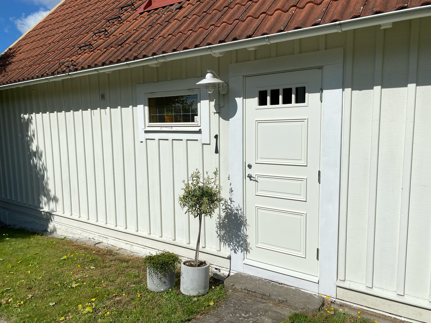 Vetlanda 7704 Vit ytterdörr modell Vetlanda 7704 från Dieden-Ekodoor monterad på klassisk träfasad med tegeltak